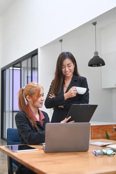 Two professionals business women discussing project developing financial research, working together in modern office.