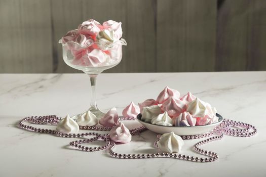 pink and white meringue candies in a vase and on a saucer, sweet still life, homemade sweets. High quality photo
