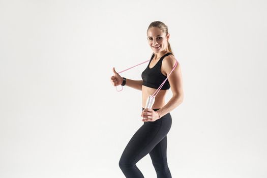 Young adult blonde girl holding a rope. The girl is engaged in fitness. Studio portrait of a girl for a healthy lifestyle.