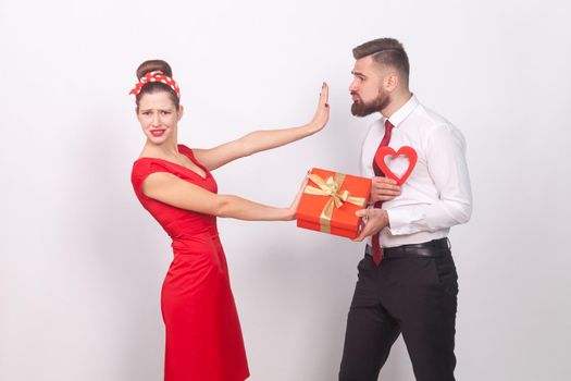 Woman in red dress, don't need present and love. Indoor, studio shot, isolated on gray background