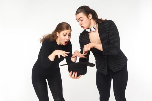 Wow! Magic inside hat. Man showing Imagination trick young woman. Studio shot, isolated on white background