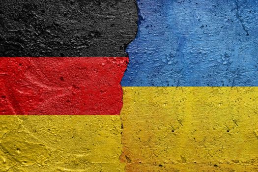 Germany and Ukraine - Cracked concrete wall painted with a Germans flag on the left and a Ukrainian flag on the right