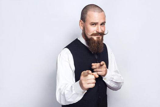 Hey you. Handsome businessman with beard and handlebar mustache looking at camera. studio shot, on gray background.