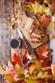 banana cake on the wooden table with orange autumn leaves, copper coffee grinder. High quality photo