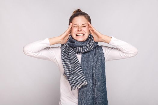 Sick woman have a headache, holding head and shout. Studio shot, isolated on gray background