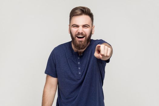 Make fun of concept. Mock, bad joke. Man pointing finger and toothy smile. Studio shot