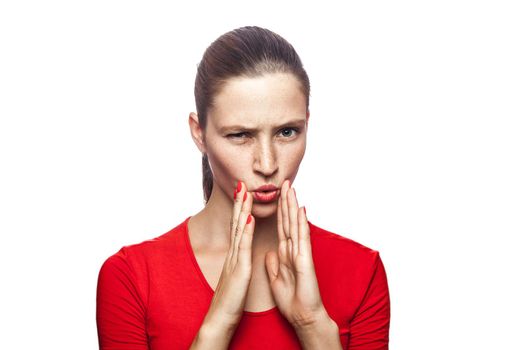 Portrait of serious woman in red t-shirt with freckles. looking at camera and telling secret, studio shot. isolated on white background.