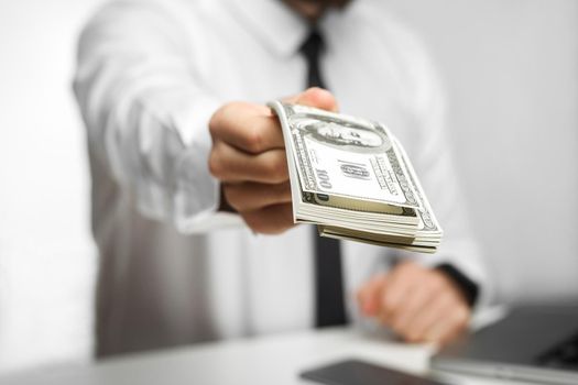 Take your money! Portrait of richman investor big boss in white shirt and black tie are sitting in office giving your a lot of money, your bonus, isolated, indoor, focus, studio shot,