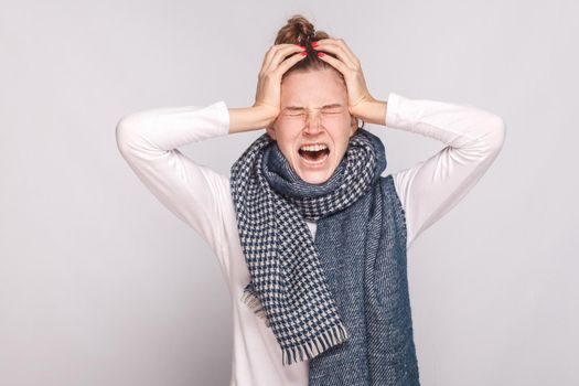 Sick woman have temperature, holding head and cry. Studio shot, isolated on gray background