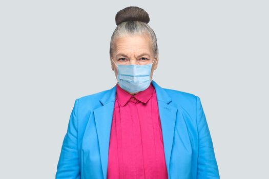 Protection against contagious disease, coronavirus. Aged woman with hygienic mask to prevent infection, airborne respiratory illness such as flu, Covid-19. indoor studio shot isolated, gray background