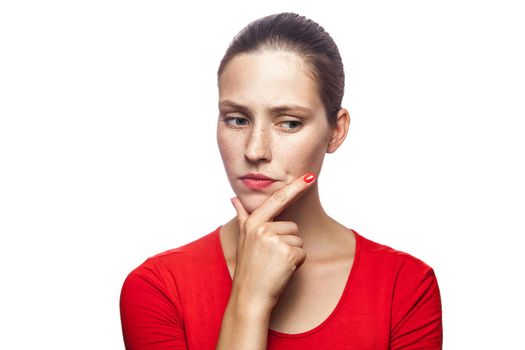 Portrait of thoughtful serious woman in red t-shirt with freckles, studio shot. isolated on white background.