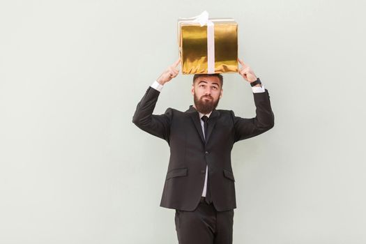 Dreaming or idea concept. Thoughtful businessman dreams and holding box on a head. Indoor shot