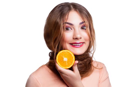Young beautiful funny girl with orange slice and makeup and hairstyle looking at camera. studio shot, isolated on white background. .