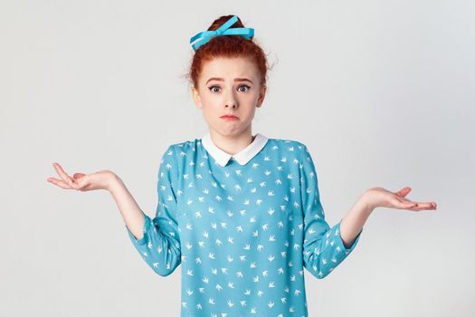Negative human emotions, facial expressions, life perception and attitude. Puzzled young redhead girl with arms out, shrugging her shoulders, saying: who cares, so what, I don't know.