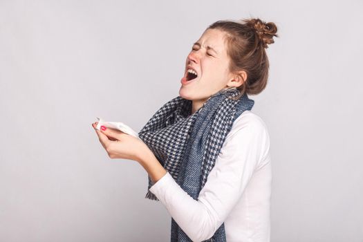 Sick woman holds a handkerchief and sneezes. Indoor shot