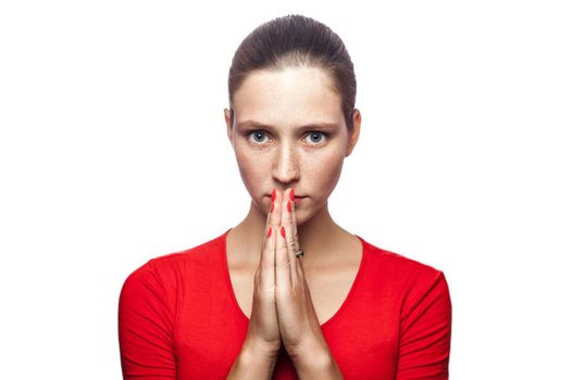 Portrait of unhappy pleasing woman in red t-shirt with freckles with shh sign. looking at camera and wishing, studio shot. isolated on white background.