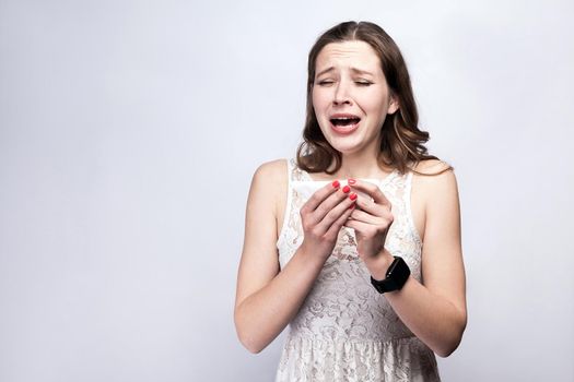 Portrait of sick cold woman with freckles and white dress and smart watch on silver gray background. healthcare and medicine concept.