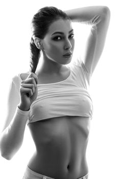 Beautiful young chinese european sexy fashion model posing in white t-shirt and undressing her white transparent shirt and looking at camera with passion. black and white photography, studio shot.