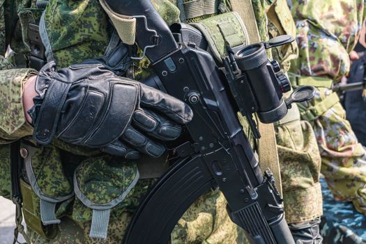 An armed soldier or airsoft player holds a combat or sporting rifle with a scope in his hands