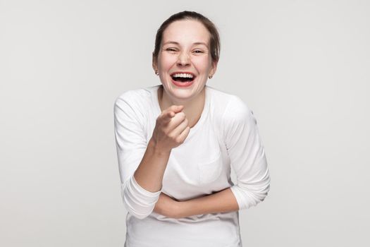 Blame you, or shame you. Girl pointing at camera and smiling. Studio shot, gray background