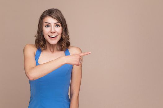 Amazement businesswoman pointing finger at copy space with shocked face. Studio shot