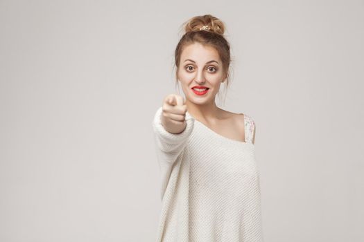 Good news. Happiness blonde woman pointing finger at camera. Studio shot, isolated on gray background