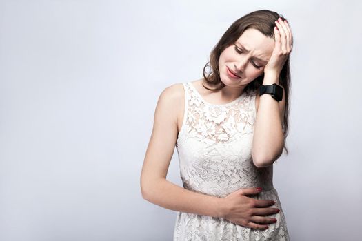 Portrait of beautiful woman with freckles and white dress and smart watch with stomach pain on silver gray background. healthcare and medicine concept.