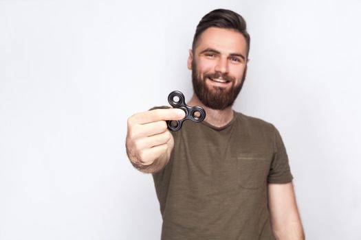 Young man holding and playing with fidget spinner. looking at camera. studio shot on white background. .