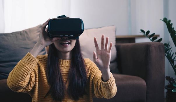 Asian woman play VR game for entertain at home, asian woman joyful in house on holiday. Happy woman playing metaverse VR technology concept..