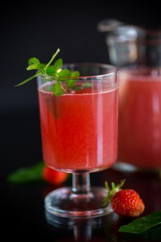 Cold summer strawberry kvass with mint in a glass isolated on black background