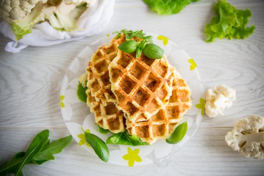 vegetable waffles cooked with cauliflower in a plate on a wooden table.
