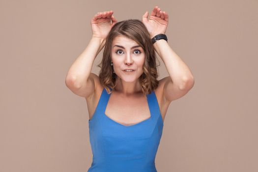 Comic woman showing rabbit sign at camera. Studio shot