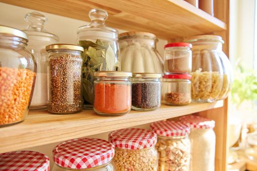 Storage of food in the kitchen in the pantry. Cereals, spices, pasta, nuts, flour in jars and containers, kitchen utensils. Cooking at home, stocking food, household