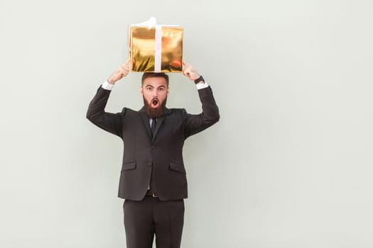 The box balances on the head a amazed businessman. Studio shot