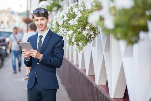 young man in business suit holding tablet on summertime day.