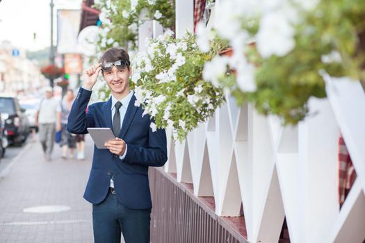 young man in business suit holding tablet on summertime day.