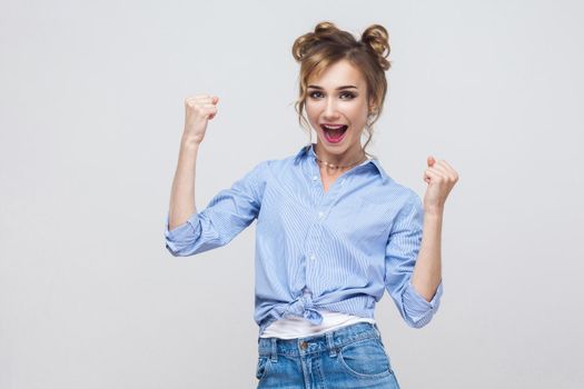 Isolated studio shot on gray background of happy successful young woman winner, feeling lucky, looking at camera, excitement and joy, smiling cheerfully.