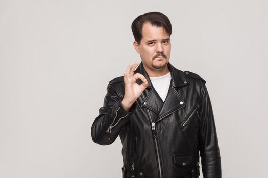 Rocker man showing okay sign and looking at camera. Studio shot