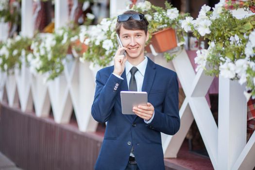 young man in business suit holding tablet on summertime day.