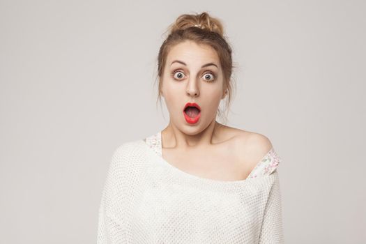 Amazement blonde open mouth and scream with surprised face. Studio shot, gray background