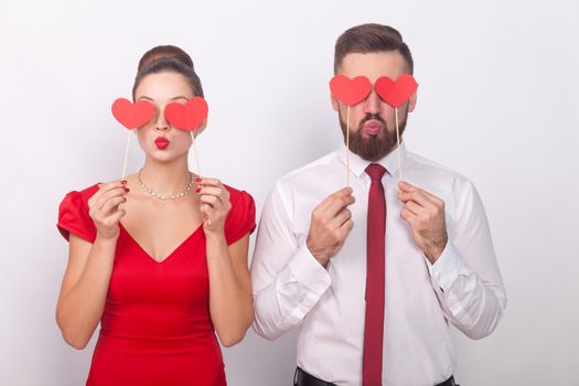 Handsome couple holding decorative sign love, heart symbol. Indoor, studio shot, isolated on gray background