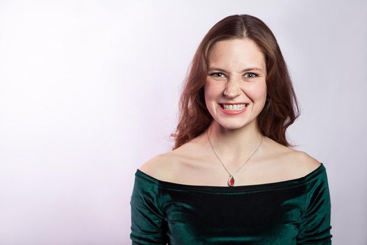 Portrait of angry woman with freckles and classic green dress. studio shot on silver gray background.