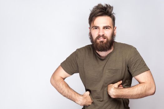 Portrait of funny crazy bearded man with dark green t shirt against light gray background. studio shot. .