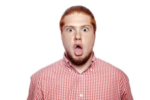 Shocked surprised bearded readhead businessman with red shirt and freckles looking at camera. studio shot isolated on white.
