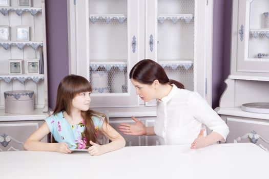 Mother and daughter quarrel because of overuse the tablet phone Social problem between parents and children. Studio shot..