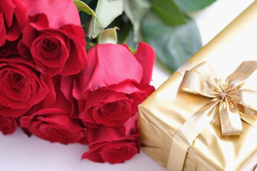 Gift box for Valentine Day tied with golden satin ribbon bow and beautiful roses. Nice gifts for women concept