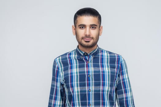 Stylish bearded man with appealing dark eyes smiling into camera. Businessman with beard grinning having positive look. Indoor, studio shot. Gray backgraund
