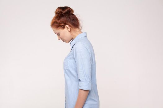 Side view, profile sad red head businesswoman. Isolated on gray background. Studio shot