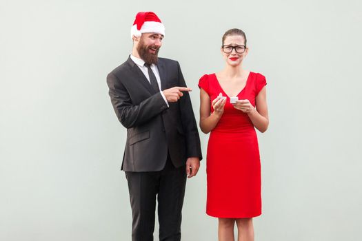 Sneer and mock concept. Man pointing fingers at woman and smiling. Woman crying and holding bad gift. Studio shot