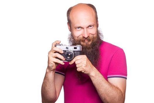 The portrait of bald bearded man photographer with pink t shirt holding classic camera. isolated on white background. studio shot.